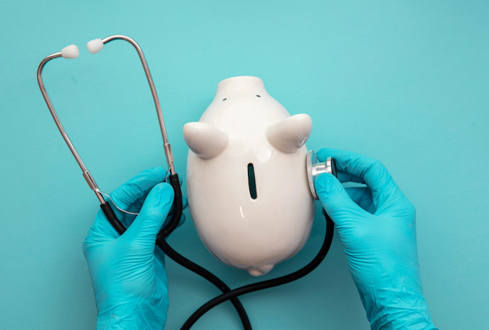 Zorgverzekering: Arts in chirurgische handschoenen met een wit spaarvarken en een stethoscoop.
